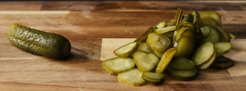 Sliced pickles on a wooden board with rustic background, highlighting freshness and simplicity.